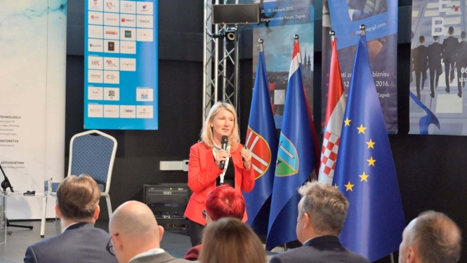 Vidzemes reģiona remigrācijas koordinatore Inga Madžule uzstājas konferencē Horvātijā sarkanā žaketē ar mikrofonu rokās.