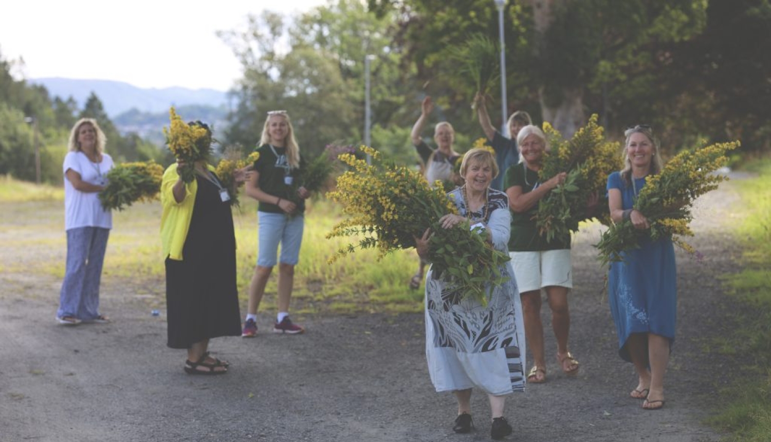 Vidzemes reģiona remigrācijas koordinatore Inga Madžule kopā ar remigrantiem rokās nes lielus dzeltenu ziedu klēpjus.
