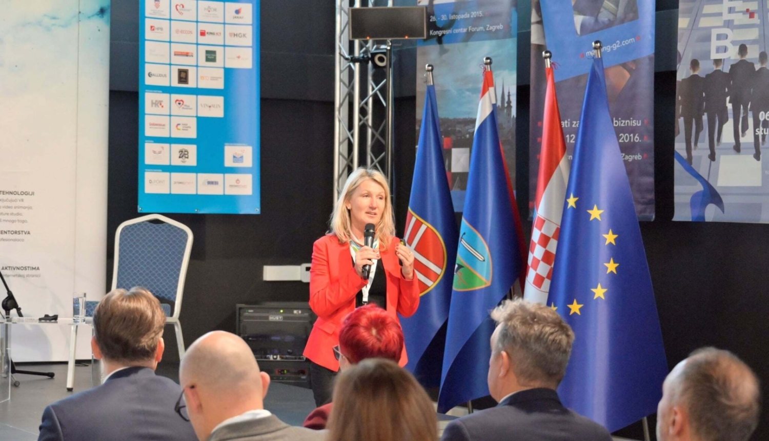 Vidzemes reģiona remigrācijas koordinatore Inga Madžule uzstājas konferencē Horvātijā sarkanā žaketē ar mikrofonu rokās.