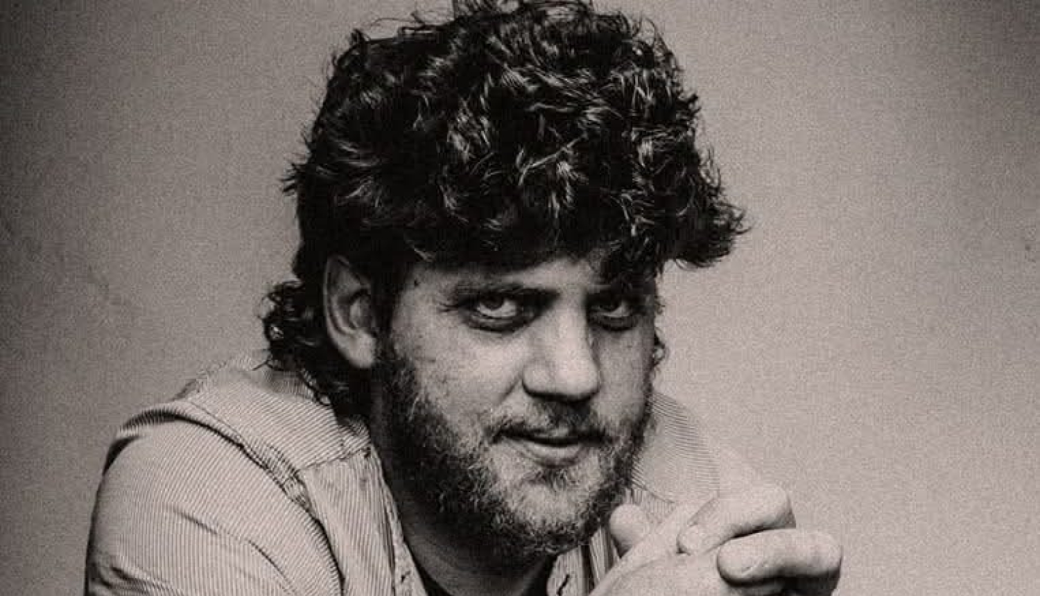 Melnbalts portrets: vīrietis ar kupliem, cirtainiem matiem